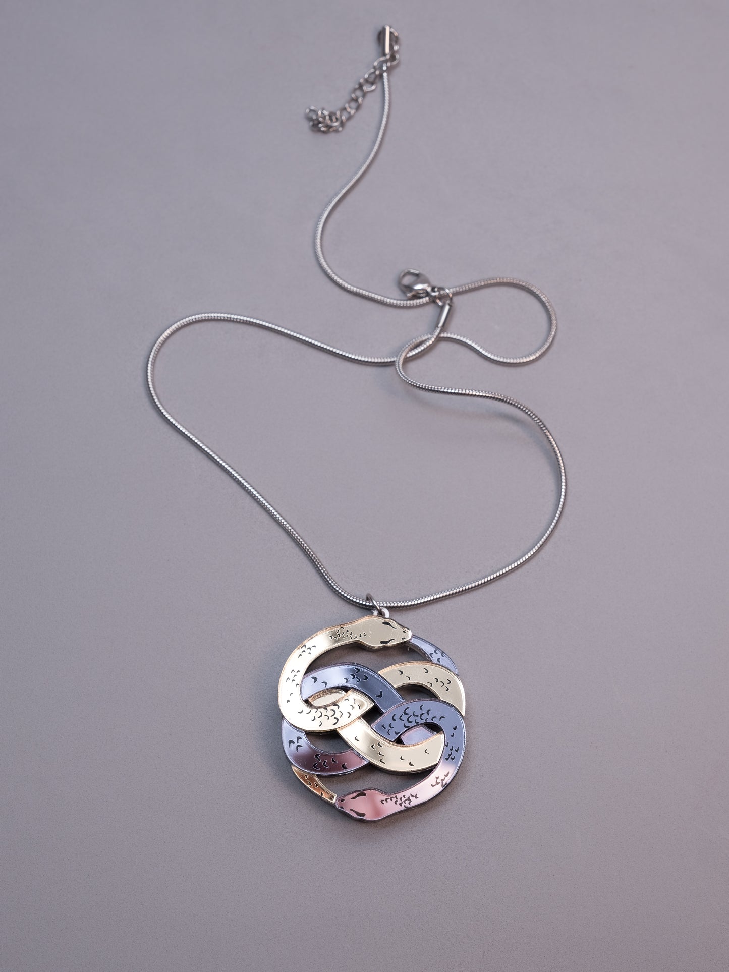 Collar de metacrilato inspirado en la historia interminable. Hecho a mano con metacrilatos espejo dorado y antracita. Con cadena cola de ratón en plateado