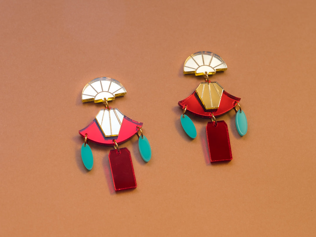 Pendientes de metacrilato rojo y dorado espejo junto con los detalles azul turquesa para hacer de estos pendientes una joya. Inspirados en la pelicula el emperador y sus locuras