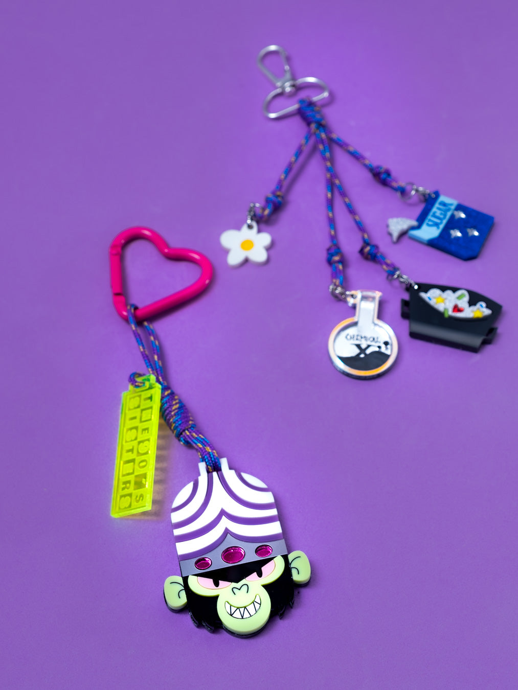 Maxillavero inspirado en Mojo Jojo el villano principal de Las Supernenas. Con mosqueton de corazón para colgarlo en us bolsos o donde quieras. tamnine disponible con accesorio para enganchar tus charms favoritos.