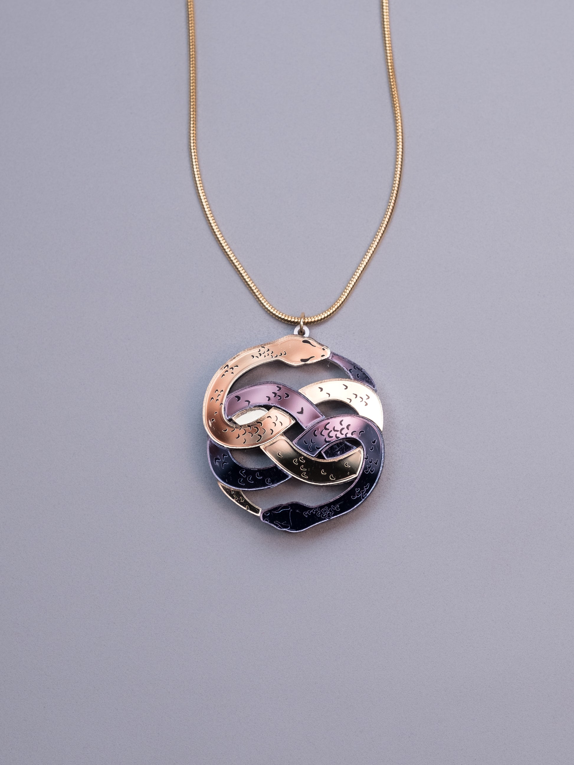 Collar de metacrilato inspirado en la historia interminable. Hecho a mano con metacrilatos espejo dorado y antracita. Con cadena cola de ratón en dorado