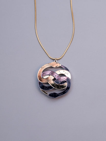Collar de metacrilato inspirado en la historia interminable. Hecho a mano con metacrilatos espejo dorado y antracita. Con cadena cola de ratón en dorado