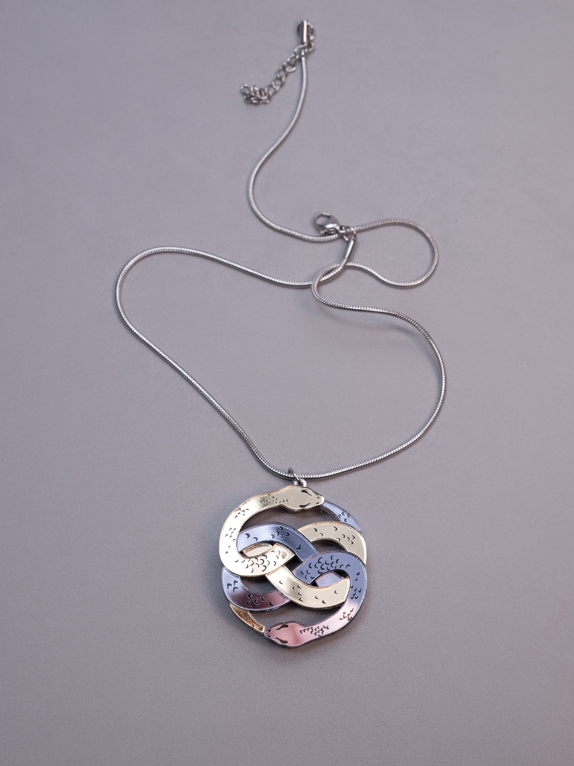 Collar de metacrilato inspirado en la historia interminable. Hecho a mano con metacrilatos espejo dorado y antracita. Con cadena cola de ratón en plateado 
