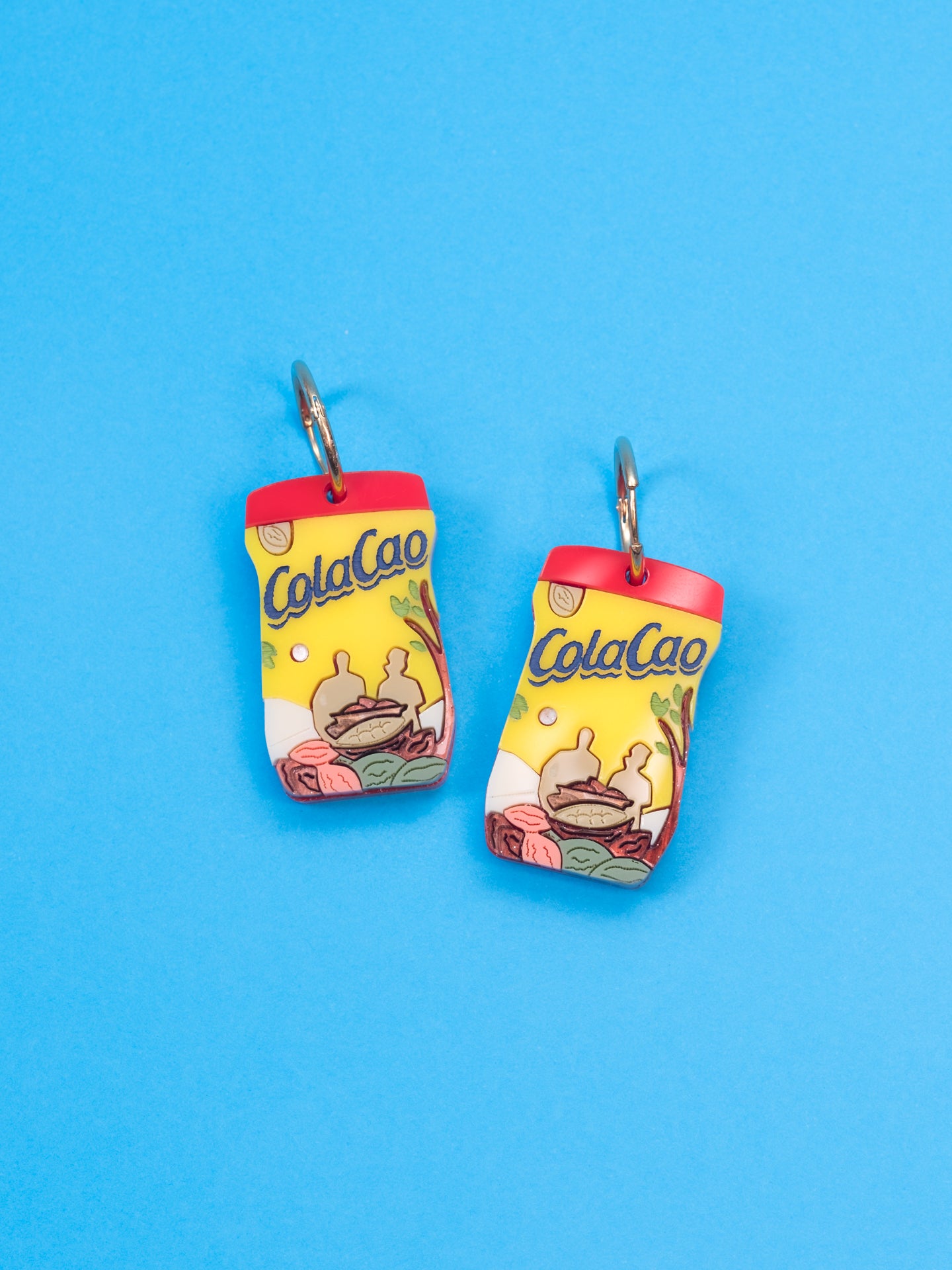 Pendientes de The90sisters x ColaCao, hechos en metacrilato con los colores del bote original de ColaCao, luce estos maxi botes de ColaCao en cualquier ocasión. Producto oficial