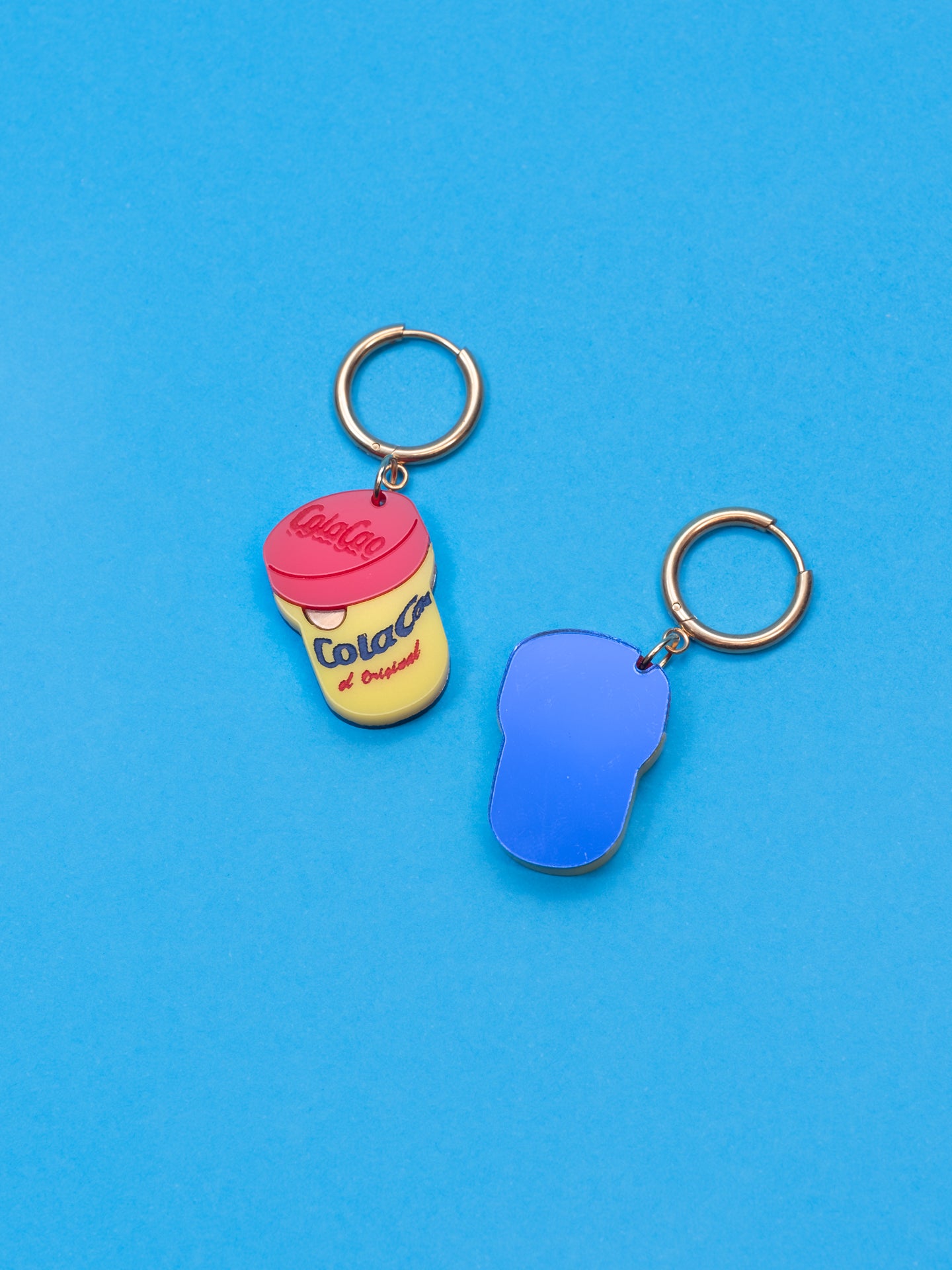 Pendientes de The90sisters x ColaCao, hechos en metacrilato con los colores del bote original de ColaCao, luce estos mini botes de ColaCao en cualquier ocasión. Producto oficial