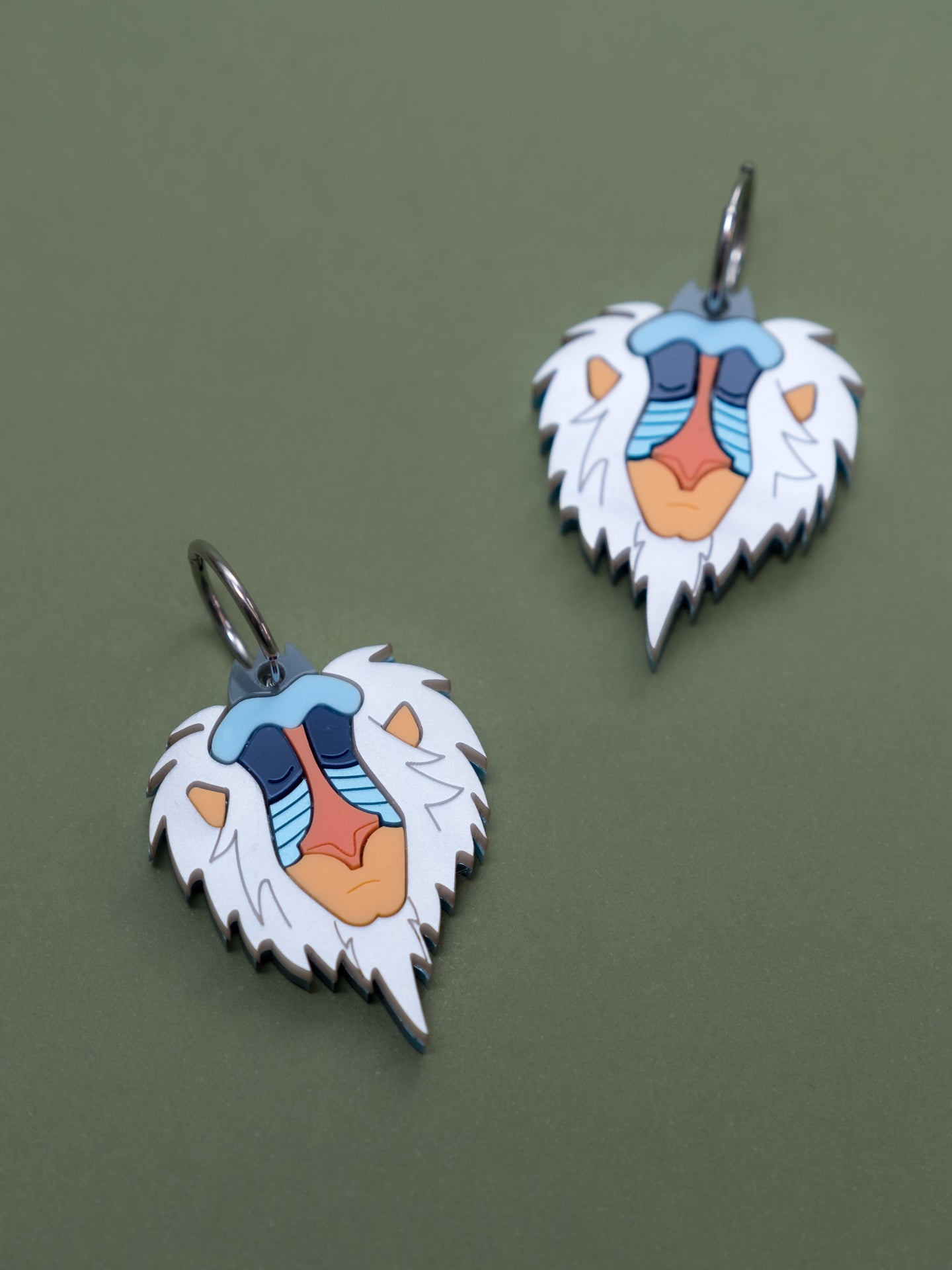 Pendientes inspirados en Rafiki el mandril más querido, en metacrilato blanco aguas naranjas y azules metalicos y brillantes.