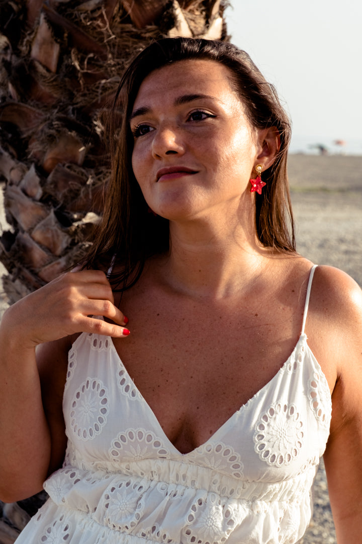 Pendientes de metacrilato rojo claro marmolado en forma de estrellita y con detalles de perlas en blanco y dorado ideales para los paseos de las vacaciones en la playa