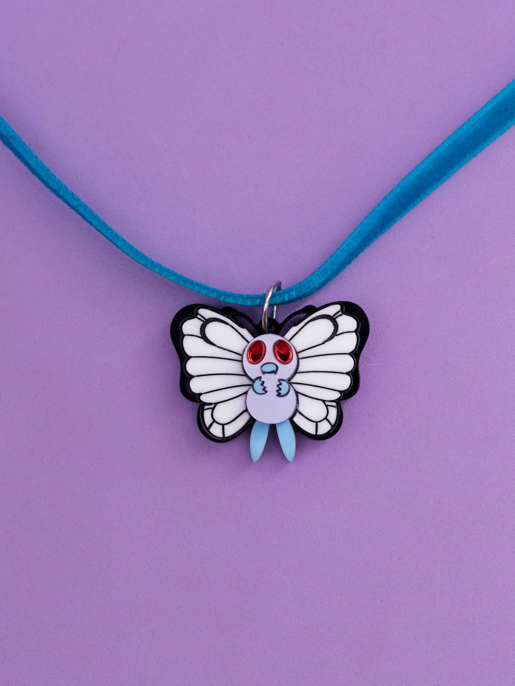 Choker de metacrilato inspirados en la serie Pokémon, en este caso el nº012 Butterfree con diferentes colores y acabados:  blanco mate, negro brillo, morado metalizado, azul mate y rojo espejo y transparente con purpurina. 
