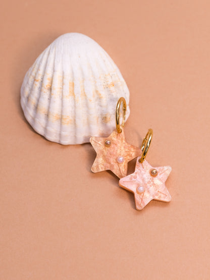 Pendientes de metacrilato naranja claro marmolado en forma de estrellita y con detalles de perlas en blanco y dorado ideales para los paseos de las vacaciones en la playa
