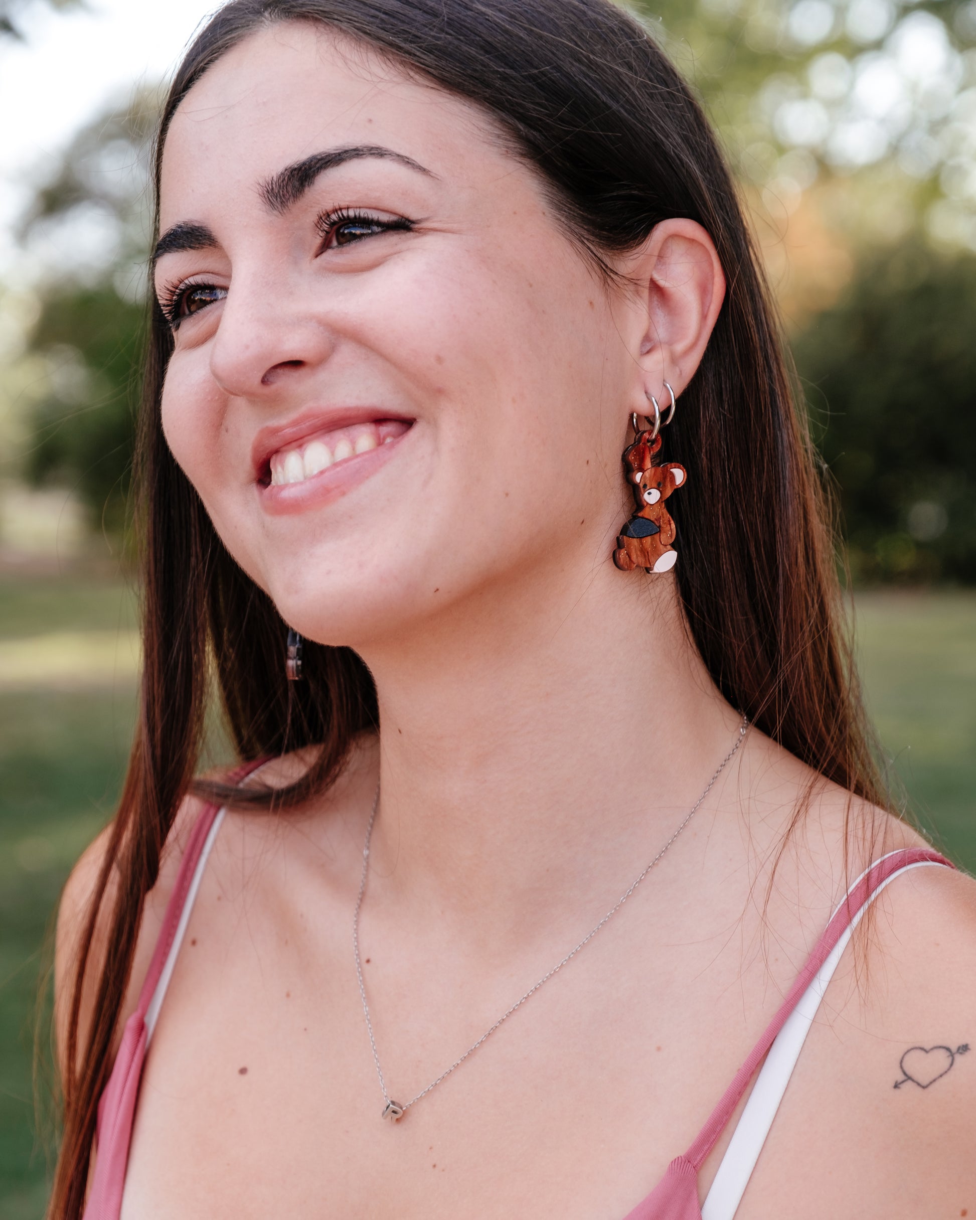 Pendientes de metacrilato inspirados en el osito de peluche de Michael de peter pan, con una bala de cañon en la barriga, en color marrón aguas con purpurina y la bala en negro piedra. foto en modelo para ver como quedan puestos