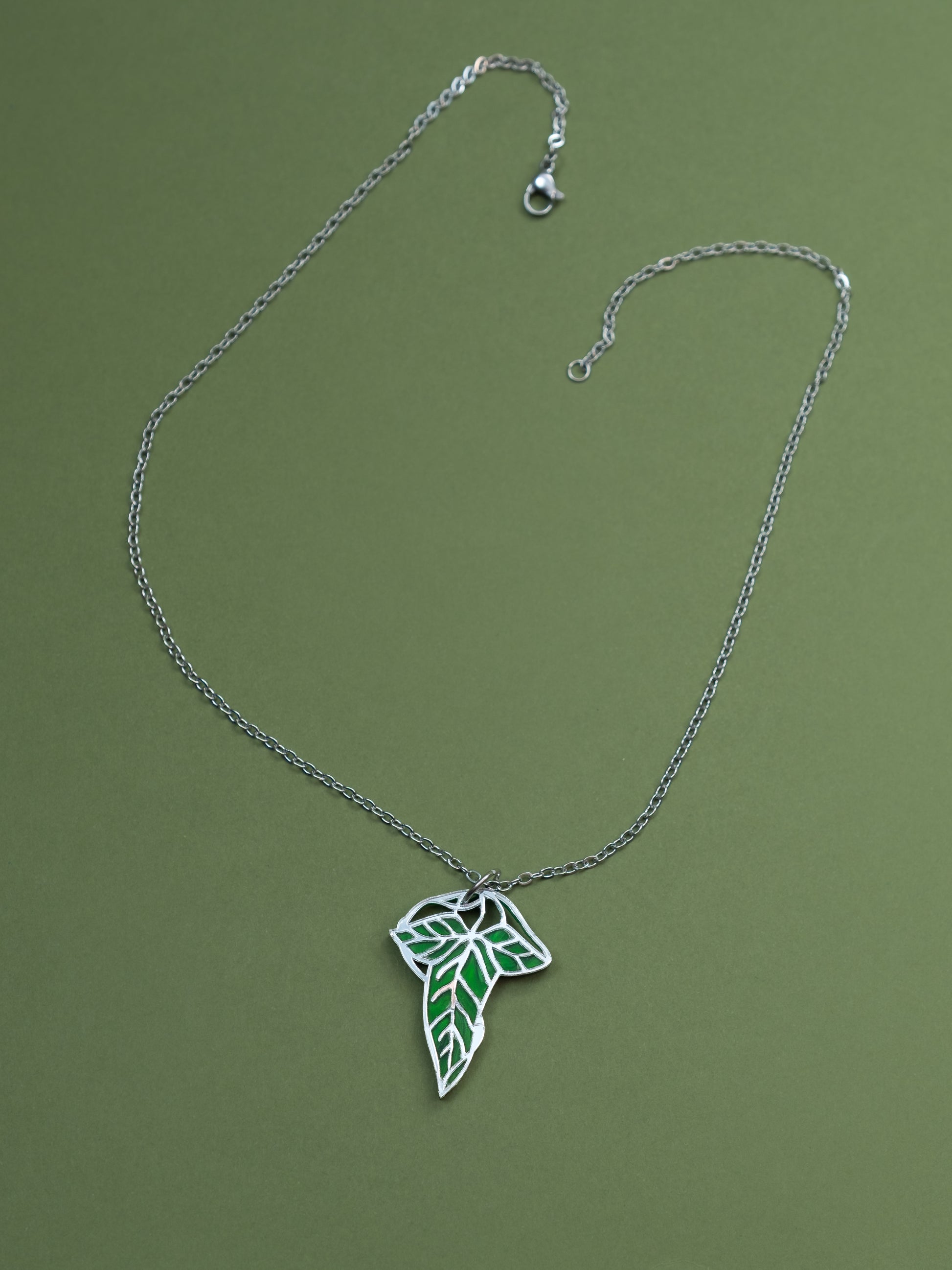 Collar de metacrilato inspirado en el señor de los anillos. La hoja esta hecha con metacrilato verde aguas y espejo plateado. Collar plateado de acero inoxidable