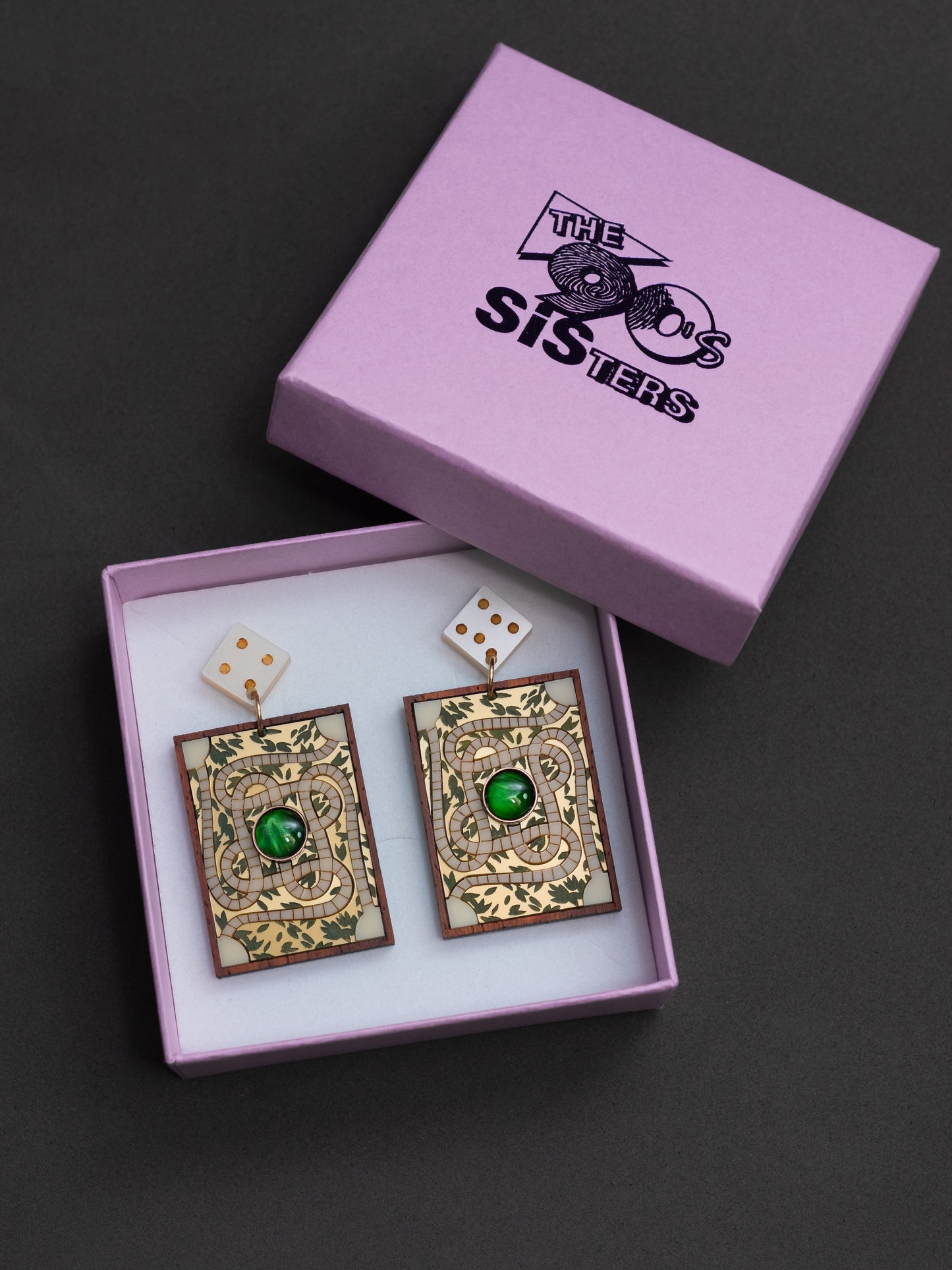 Pendientes de metacrilato inspirados en la famosa película de jumanji. Representamos el tablero de juego con piezas de diferentes colores y tipos de material. Guardados en su caja