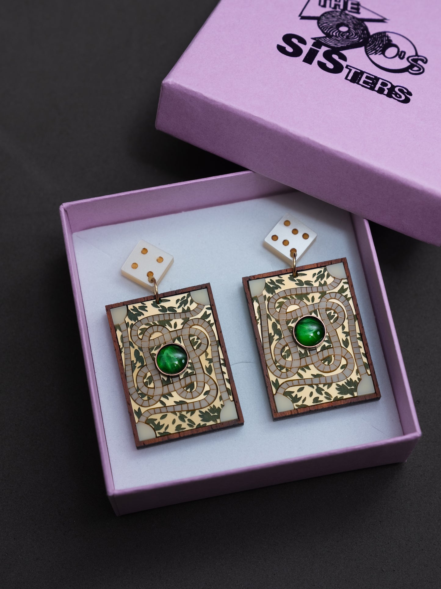 Pendientes de metacrilato inspirados en la famosa película de jumanji. Representamos el tablero de juego con piezas de diferentes colores y tipos de material. Guardados en su caja