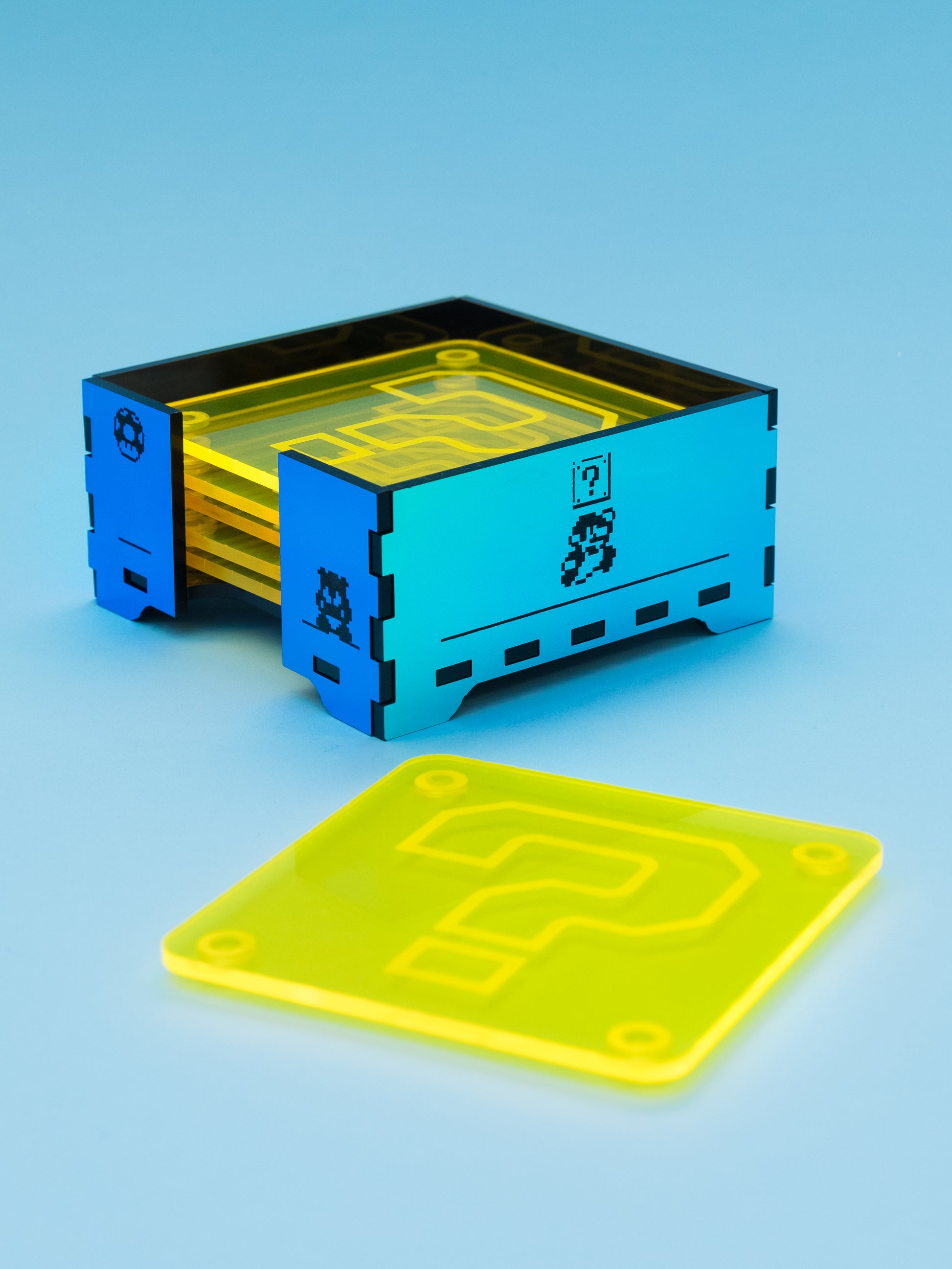 Posavasos de metacrilato inspirados en mario bros, los posavasos son amarillo fluor con su gotas antideslizantes y la caja en metacrilato espejo iridiscente con grabados de escenas de mario