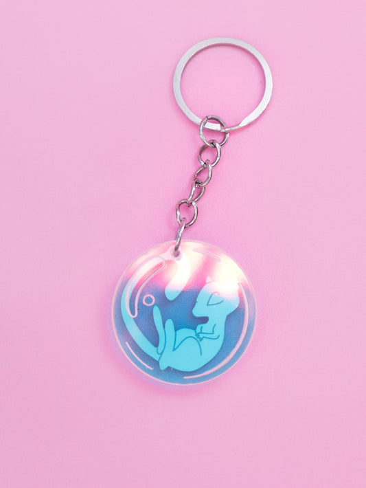 Llavero de metacrilato inspirado en la serie Pokémon, en este caso el nº151 Mew en rosa metalizado y burbuja en iridiscente. Con llavero de acero inoxidable