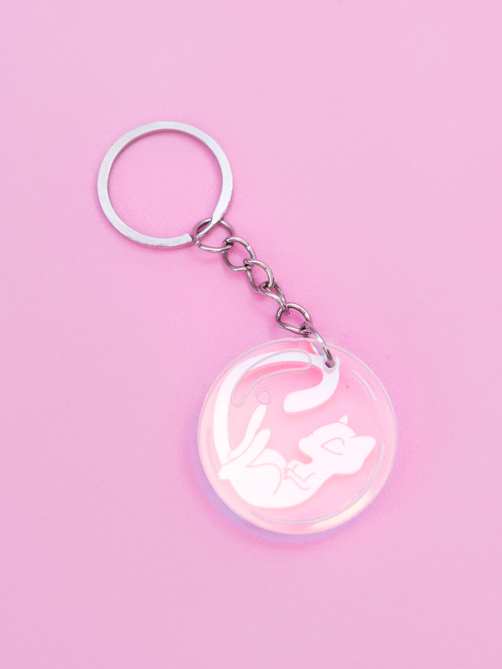 Llavero de metacrilato inspirado en la serie Pokémon, en este caso el nº151 Mew en rosa metalizado y burbuja en iridiscente. Con llavero de acero inoxidable