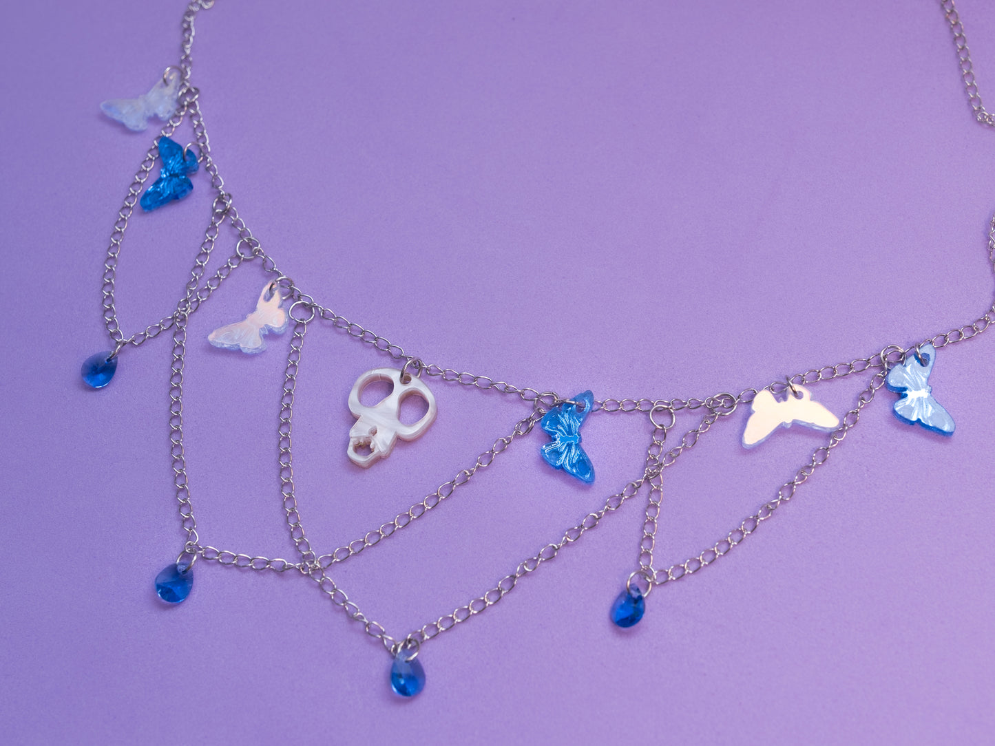 Collar de metacrilato y acero inox. inspirado en las películas de Tim Burton, mariposas espejo, azul e iridiscente culminadas con cristales gota azul y la cabeza de Scraps en el centro para dar ese aspecto elegante y spooky